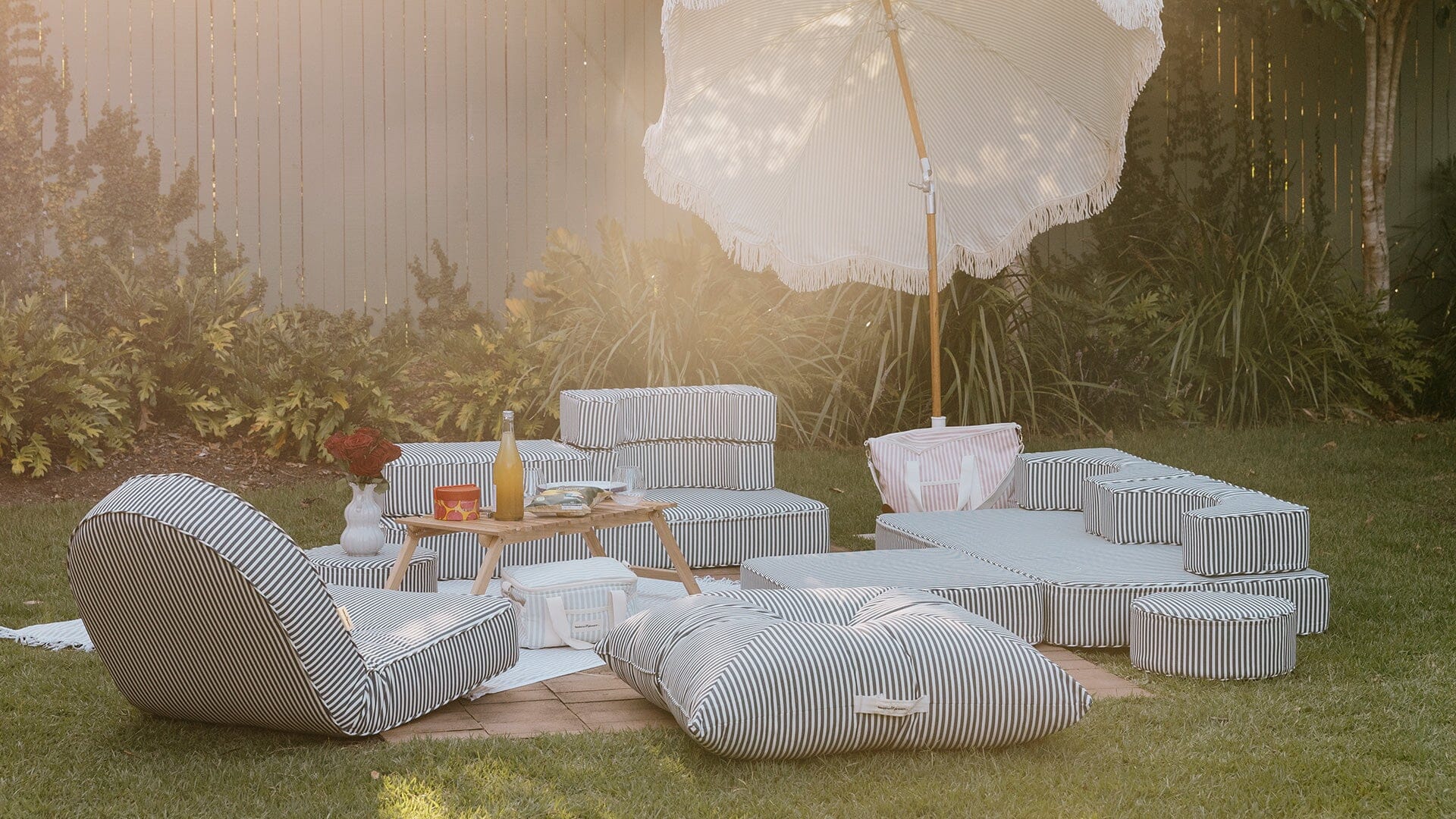 A pillow and recliner layout on the lawn under an umbrella
