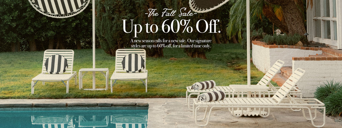 Outdoor poolside scene with white lounge chairs and striped pillows on a patio beside a swimming pool, with a house and trees in the background and promotional text reading 'The Fall Sale Up to 60% Off.'.