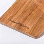 Wooden cutting board with 'business & Pleasures' branding on a white background