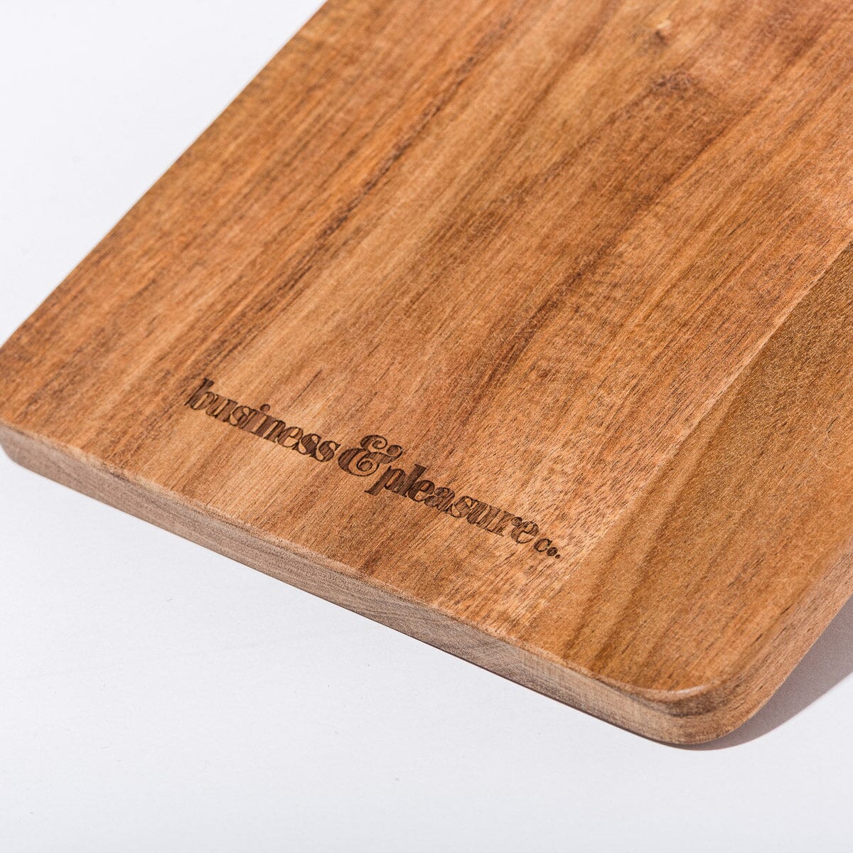 Wooden cutting board with 'business & Pleasures' branding on a white background