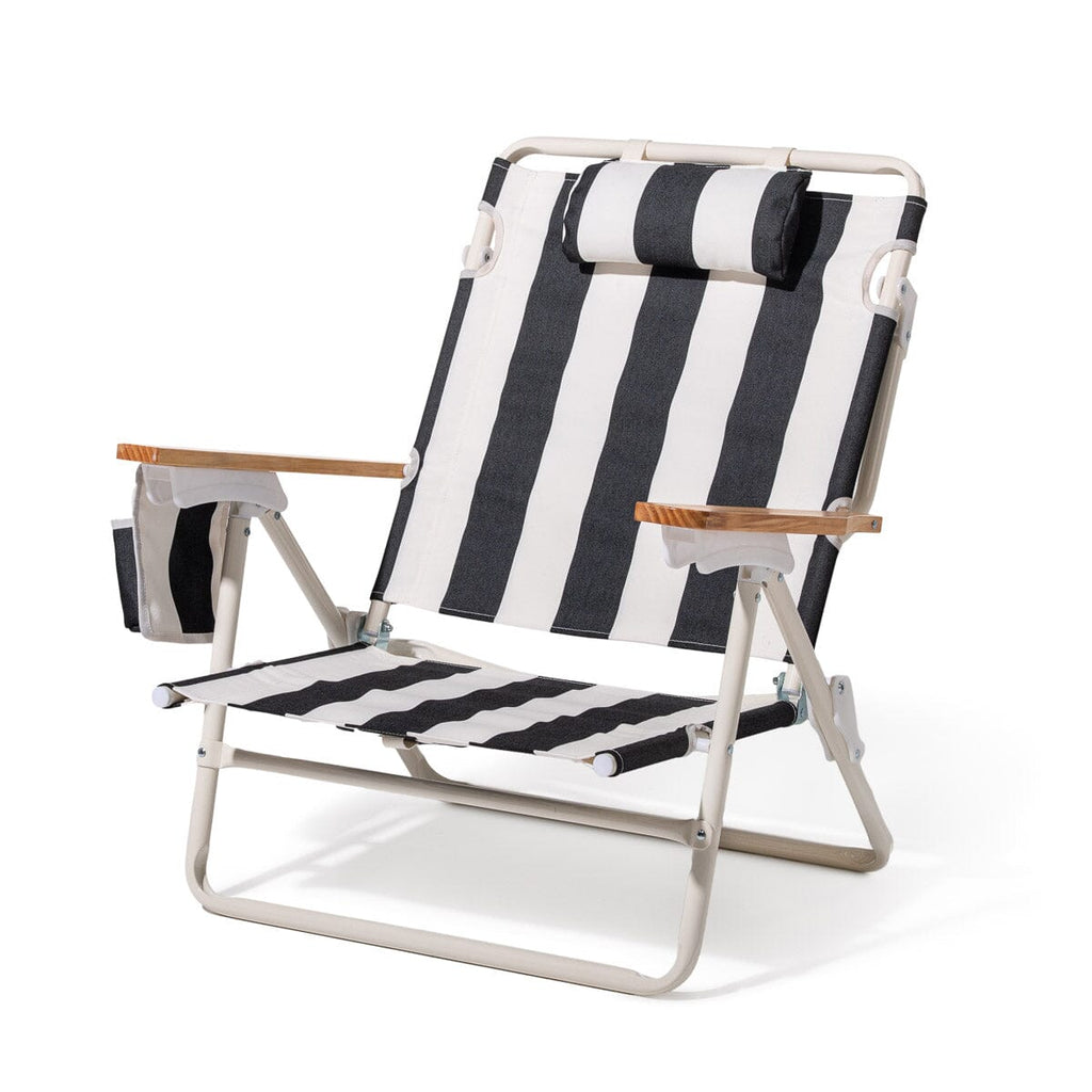 Black and white striped beach chair with wooden armrests on a white background