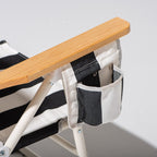 Chair with wooden arms and black and white striped seat on a light gray background