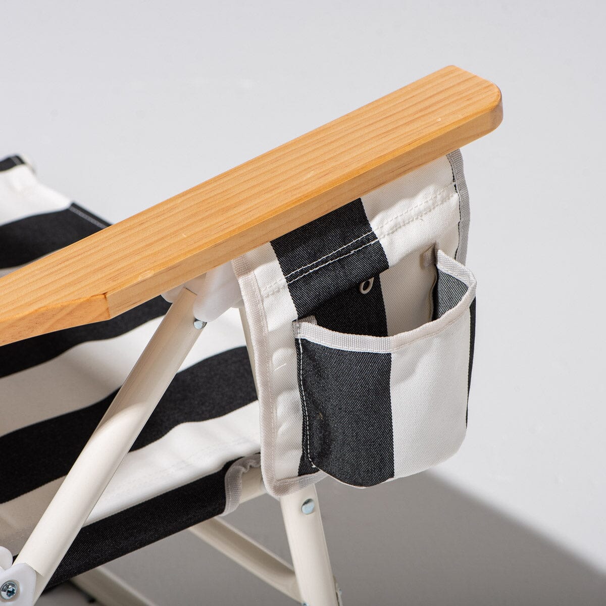 Chair with wooden arms and black and white striped seat on a light gray background
