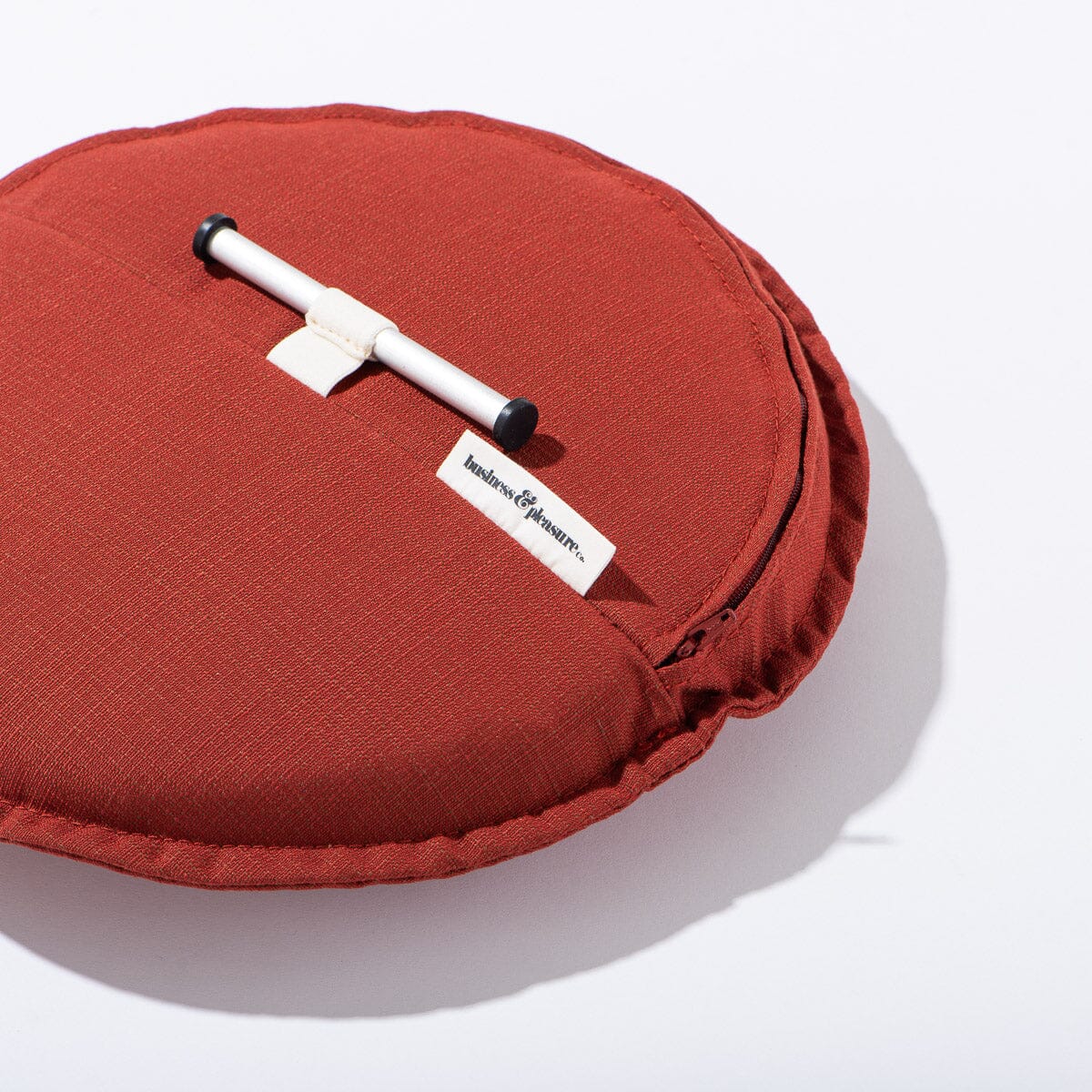 Red cushion with a white handle and visible brand label on a white background