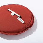 Red cushion with a white handle and visible brand label on a white background