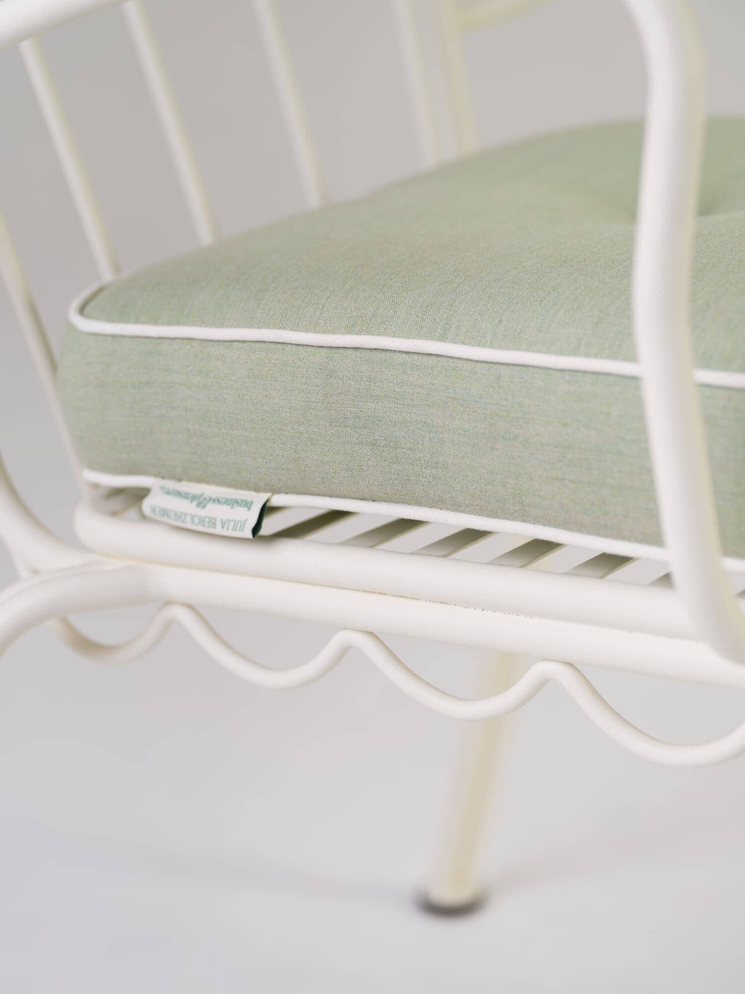 Close up detail of green chair cushion on white metal chair in studio