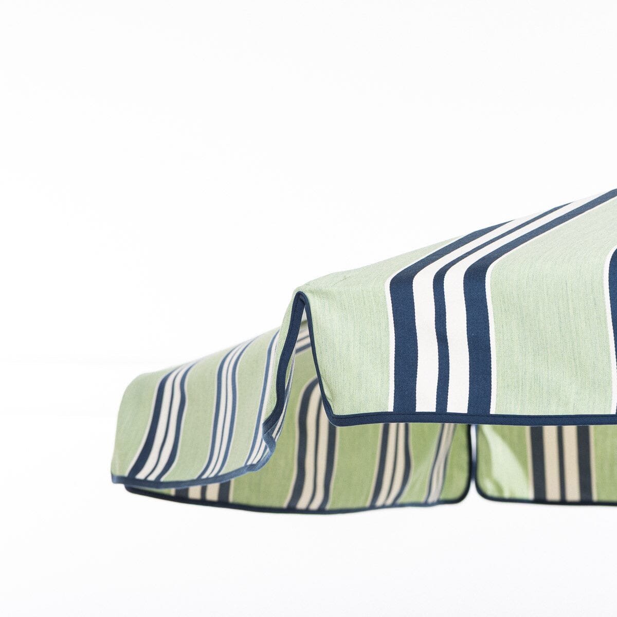 close up of the umbrella edge and its  striped fabric with green, blue, and beige colors on a white background