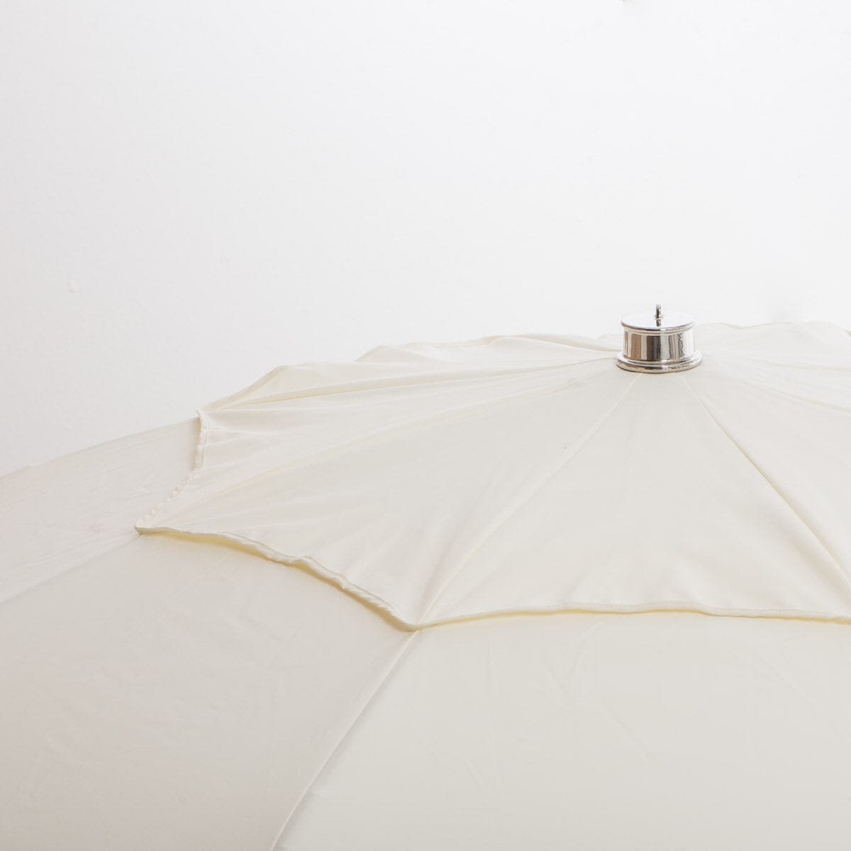 close up of chrome top cap on white patio umbrella