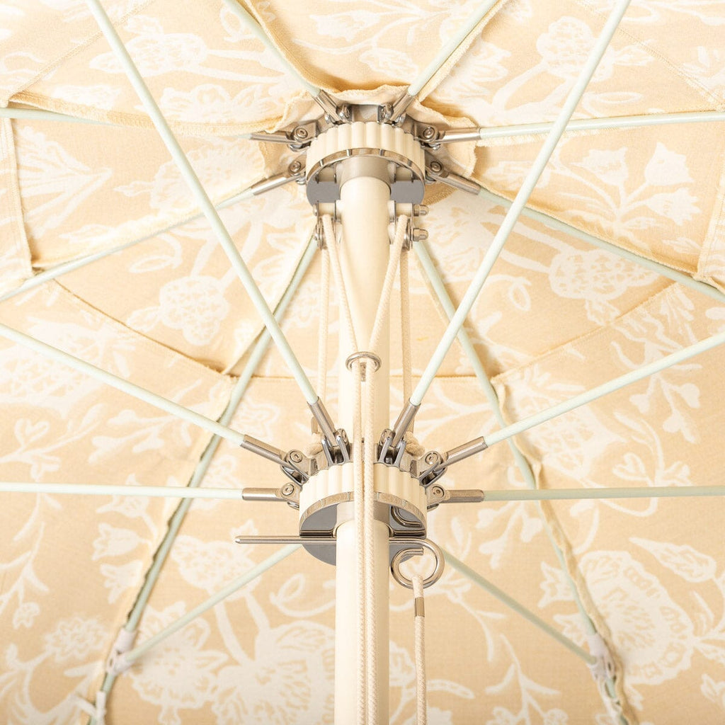 Close-up of a patio umbrella finial and arms with beige and white floral fabric in the background