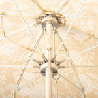 Close-up of a patio umbrella finial and arms with beige and white floral fabric in the background