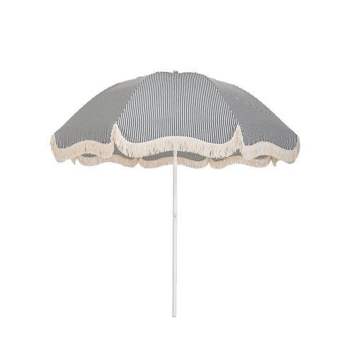 Business & Pleasure Co. Patio Umbrella in Laurens Navy Stripe, featuring a dome-shaped canopy with fine navy and white stripes, scalloped edges, cream fringe trim and a white center pole.