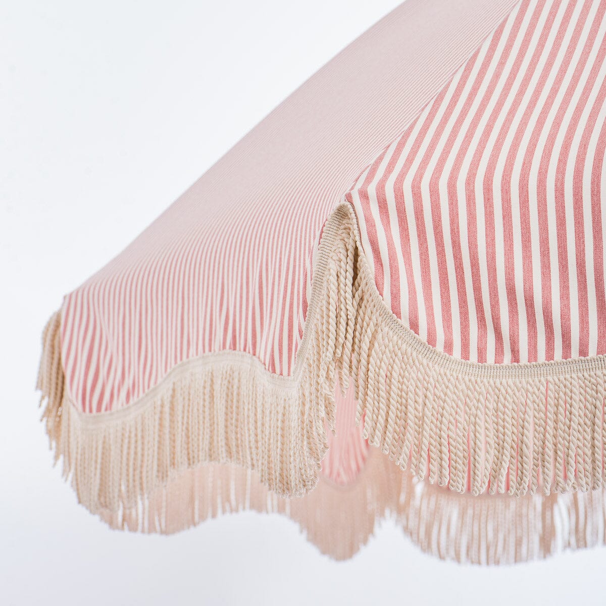 close up of fringe on pink stripe patio umbrella