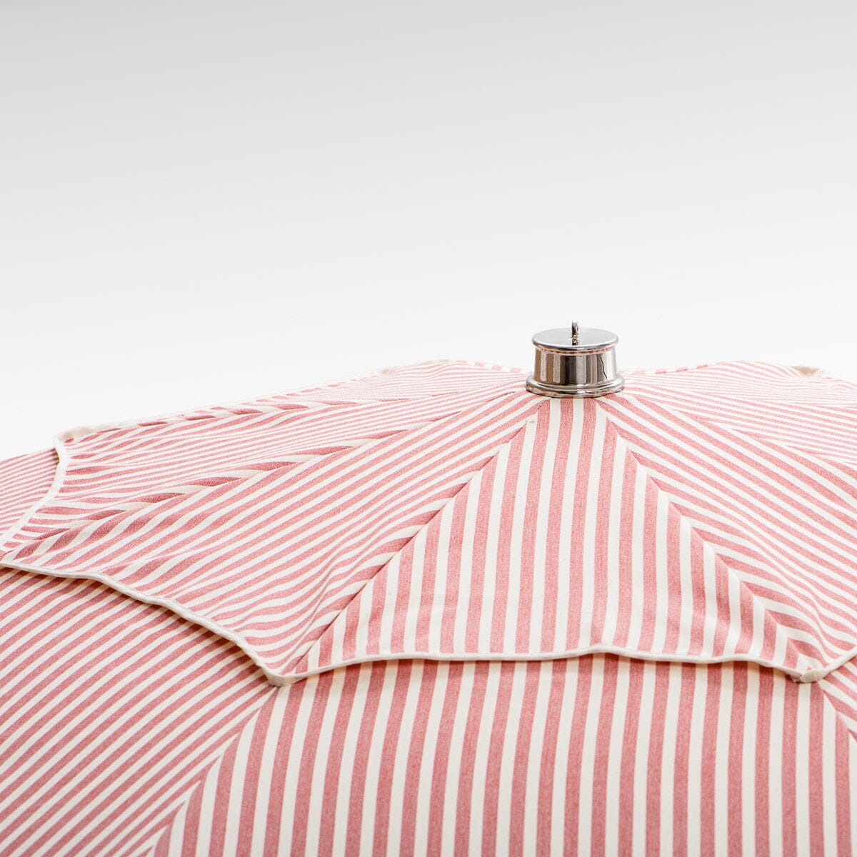 chrome top cap detail on pink stripe patio umbrella