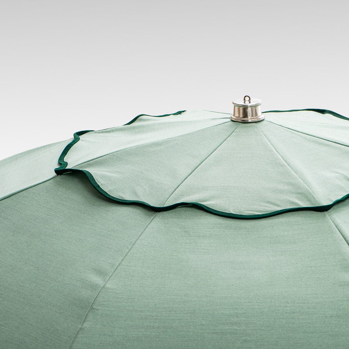 chrome top cap detail on green patio umbrella