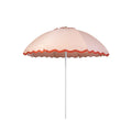 Business & Pleasure Co. Patio Umbrella in Rivie Pink, featuring a dome-shaped blush pink canopy with scalloped edges, contrasting terracotta red wave trim and a white center pole.