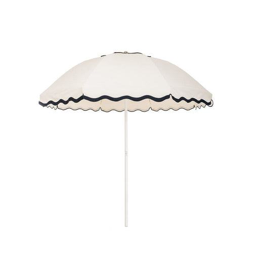 Business & Pleasure Co. Patio Umbrella in Rivie White, featuring a dome-shaped ivory canopy with scalloped edges, contrasting dark navy wave trim and a white center pole.**