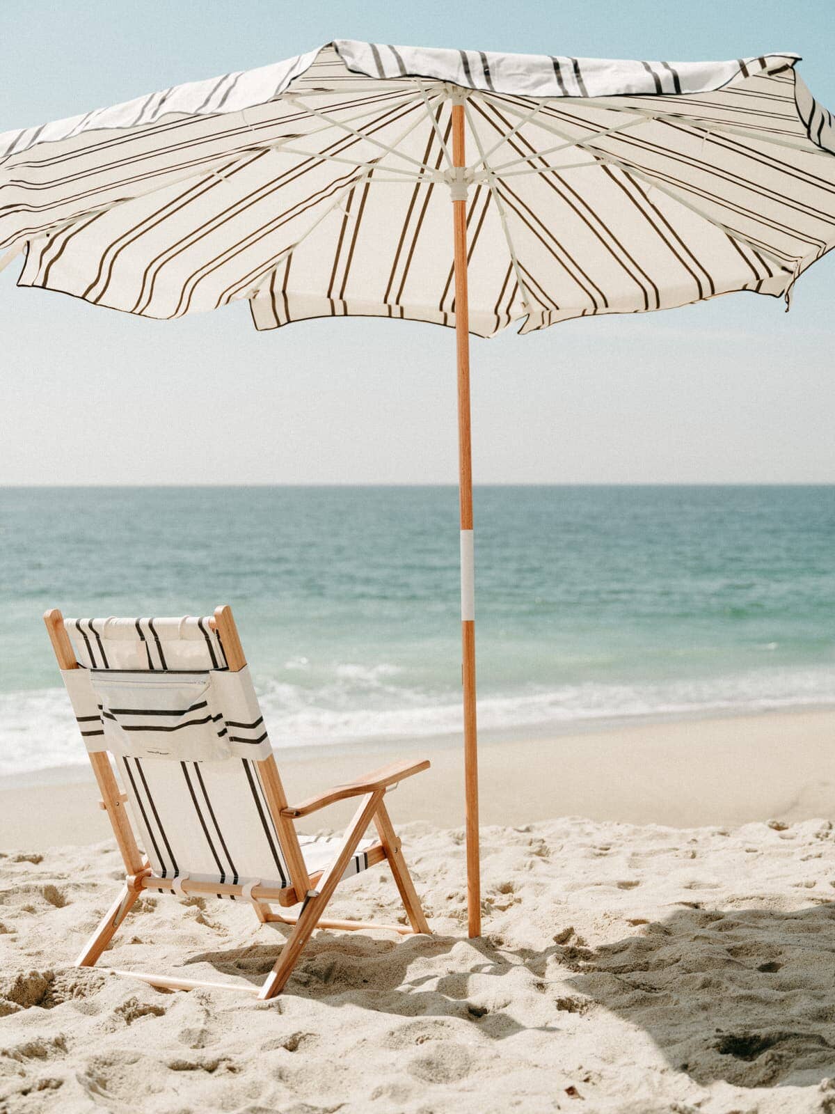 black two stripe amalfi umbrella and tommy chair on the beach