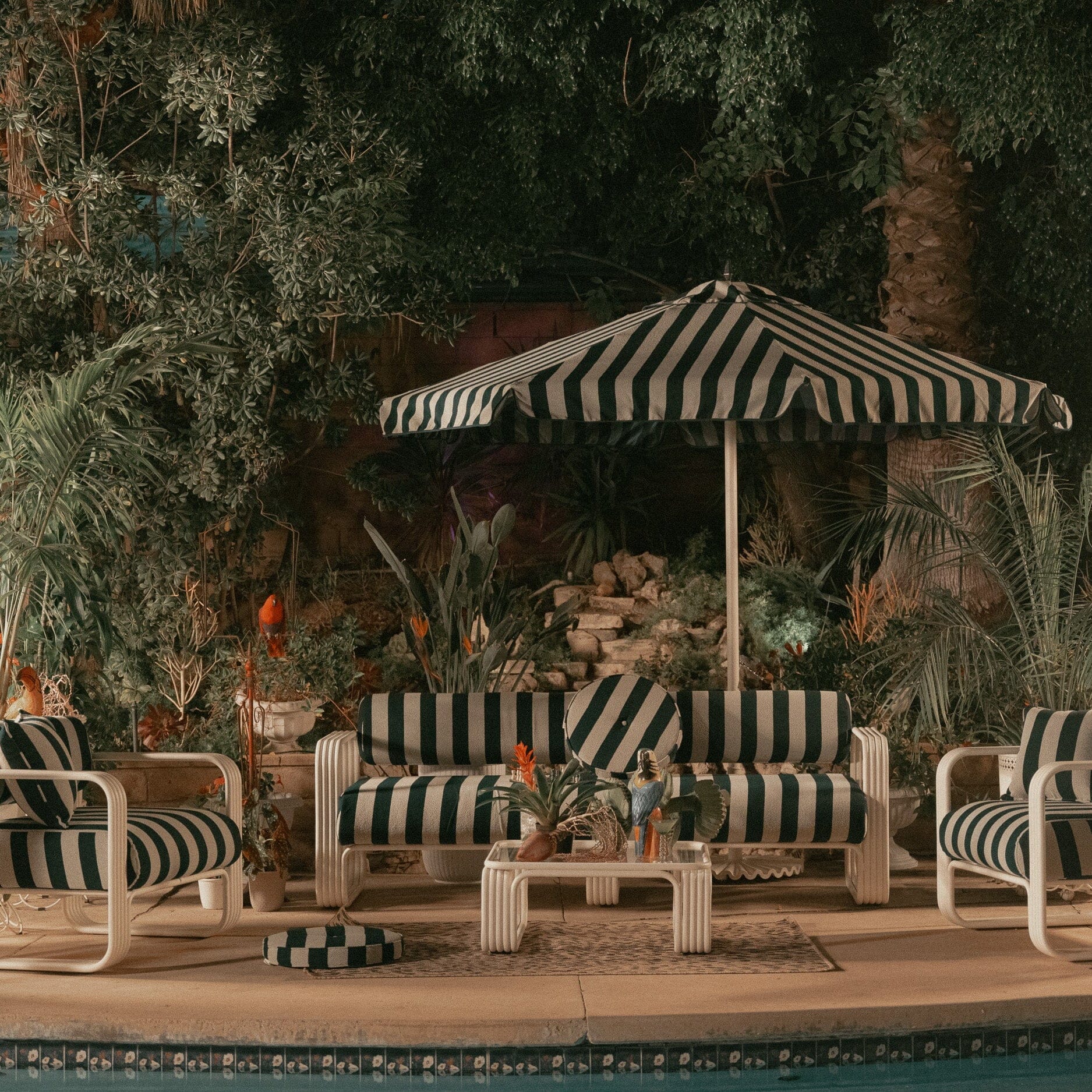 Product image of Outdoor patio set with striped furniture and umbrella near a pool