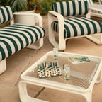 Outdoor setting with striped chairs and a chessboard on a table.