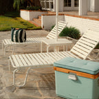 Outdoor patio scene with lounge chairs and a round teal mirror.