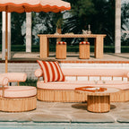 Outdoor patio setting with wooden furniture, striped cushions, and a large umbrella.