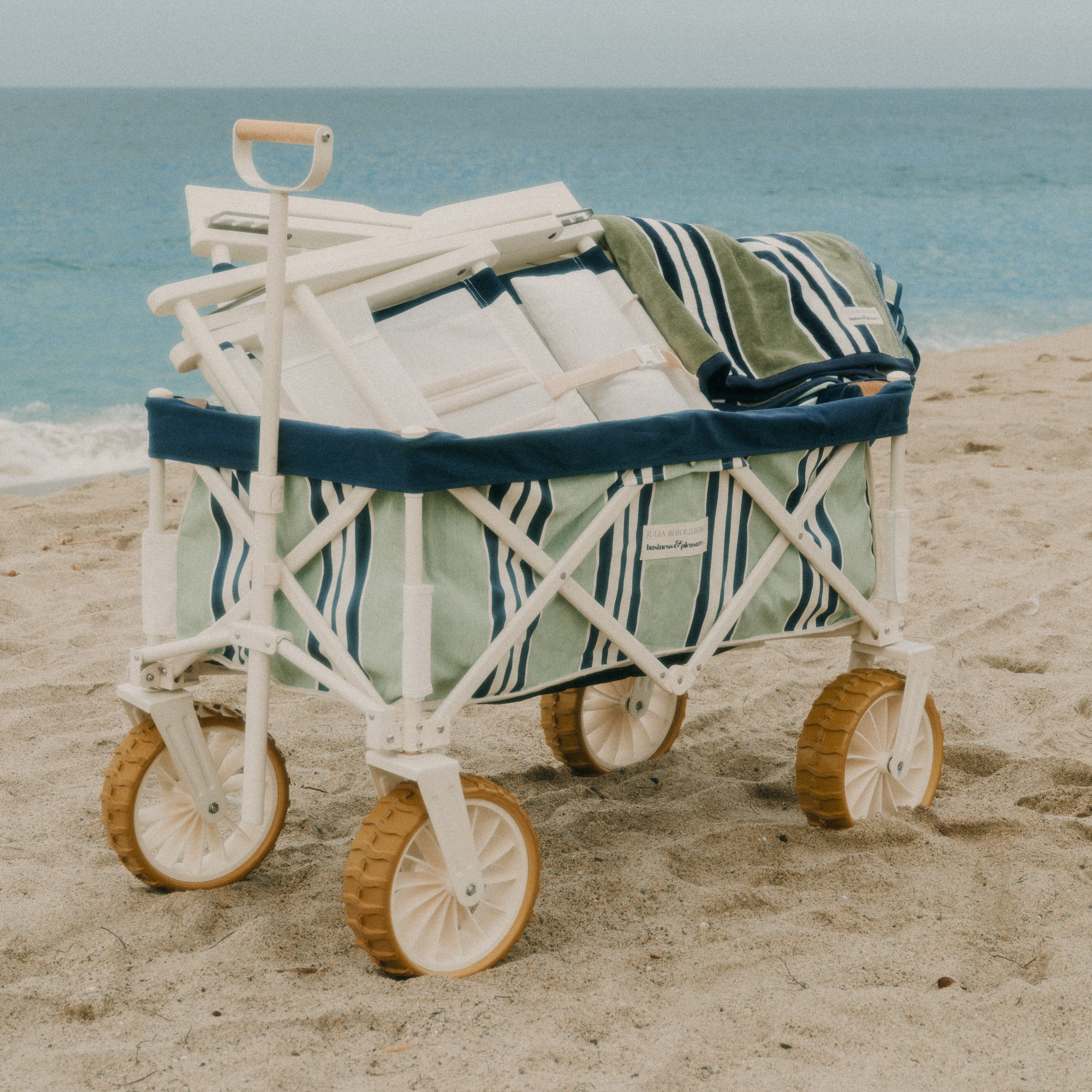 Beach cart with folded chairs on a sandy beach with ocean in the background