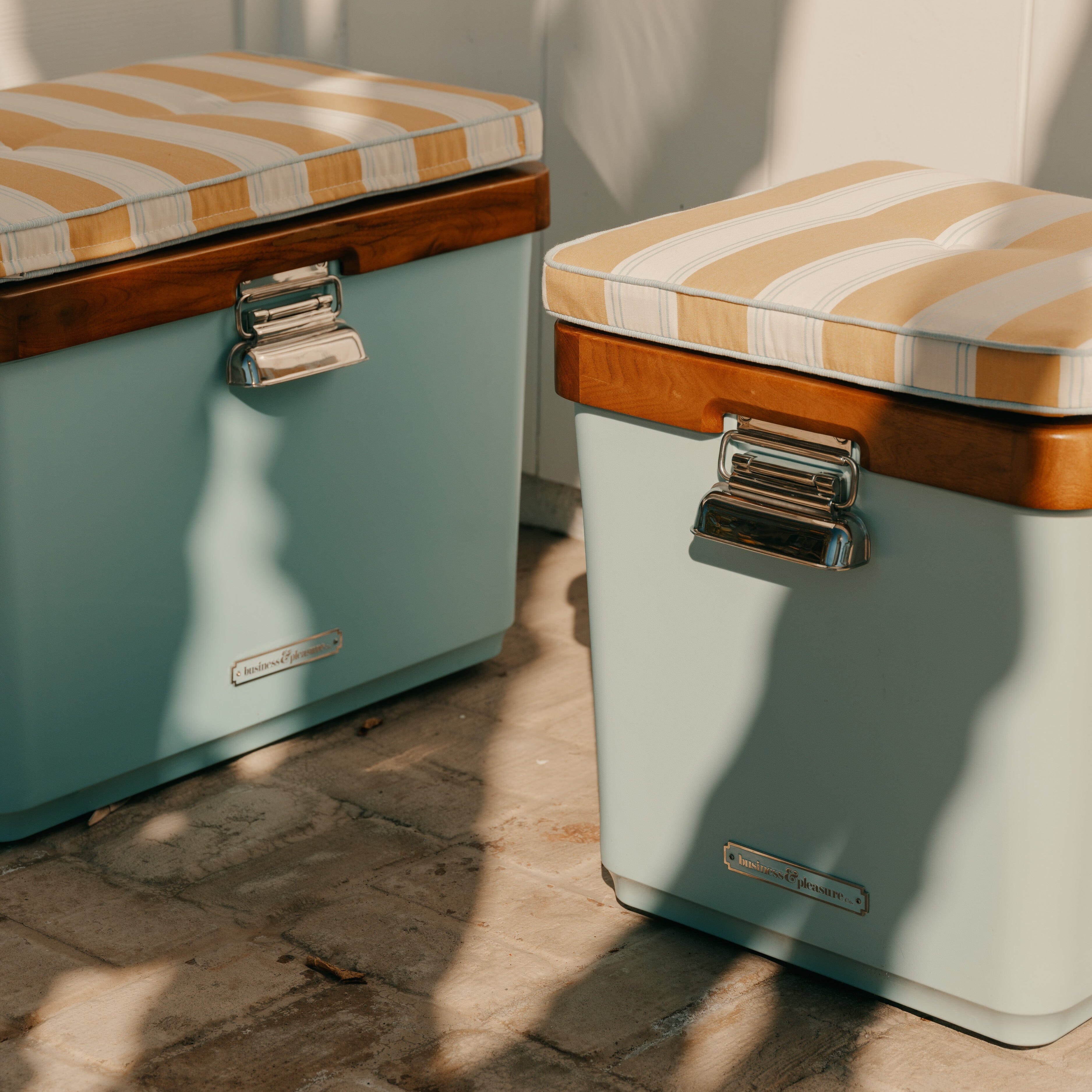 Two vintage-style coolers with striped lids on a stone floor.