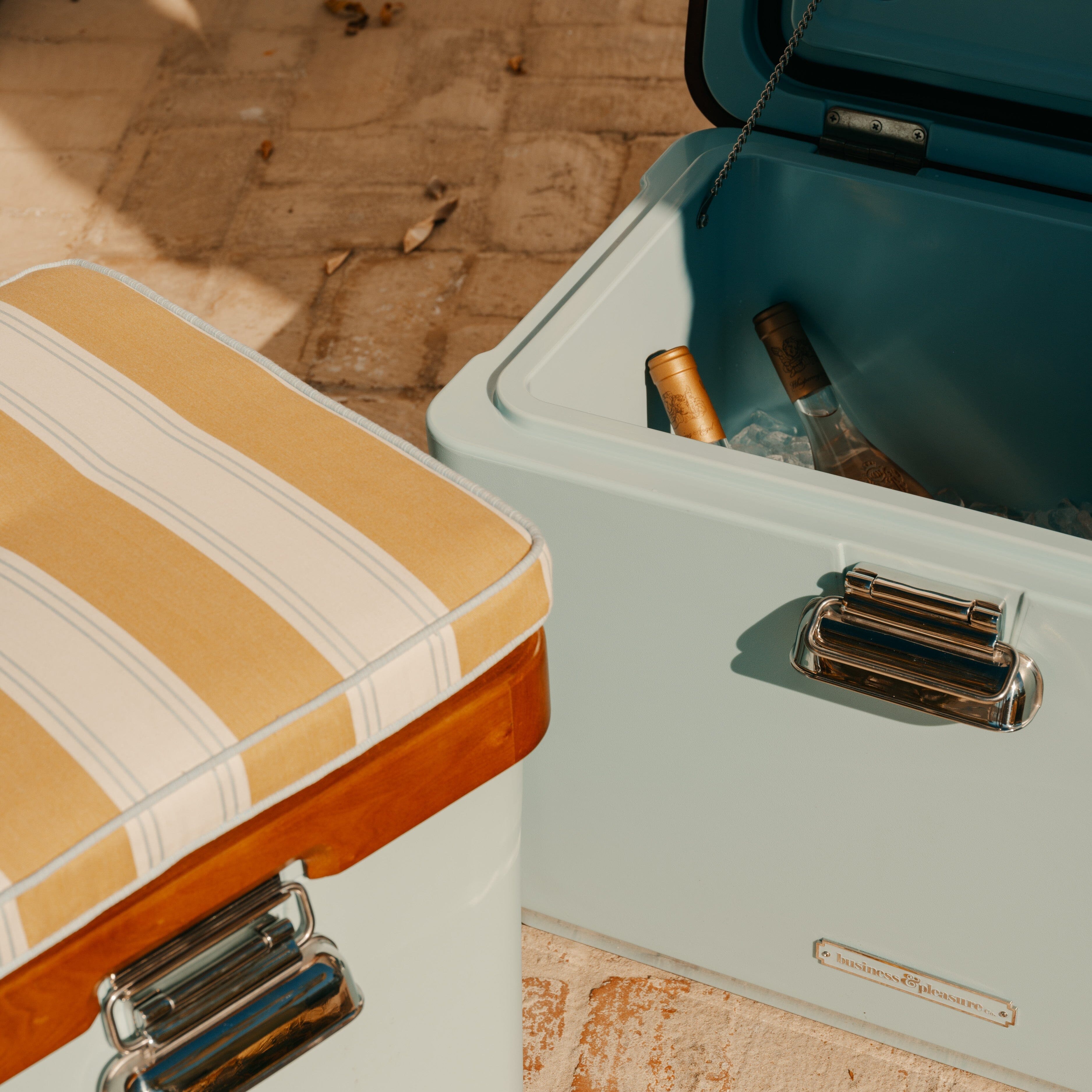 Two vintage suitcases on a wooden floor with sunlight casting shadows.