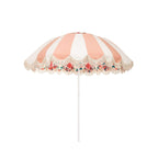 Business & Pleasure Co. Patio Umbrella in Palm Royal, featuring a dome-shaped canopy with alternating blush pink and white panels, scalloped edges, cream fringe, a colorful floral underside and a white center pole.