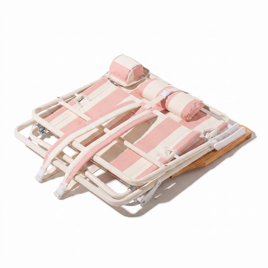 Pink and white beach chair folded down to show backpack straps on a white background