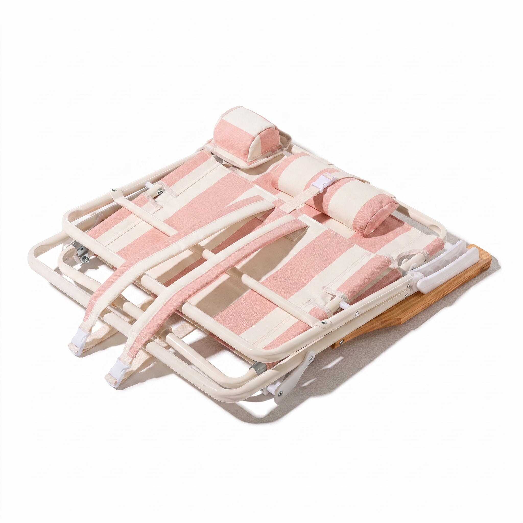 Pink and white beach chair folded down to show backpack straps on a white background