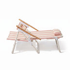 Pink and white striped lounge chair with wooden armrests on a white background