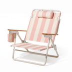 Pink and white striped beach chair with wooden armrests on a white background