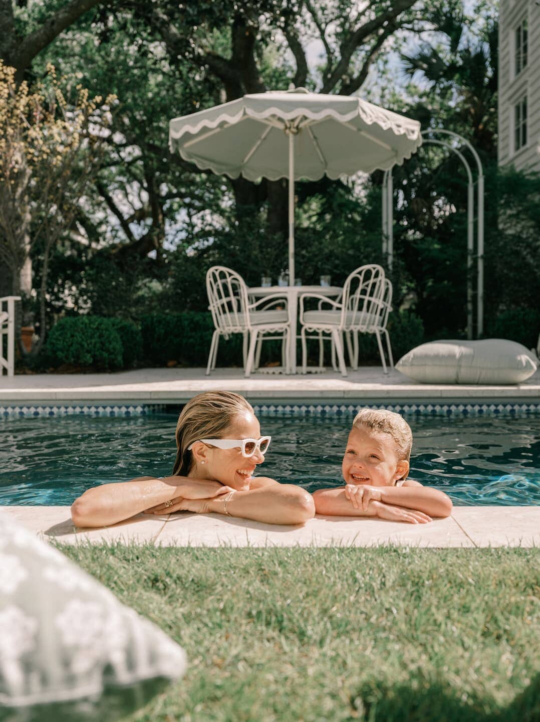 Mother and daughter in pool with outdoor furniture on the patio