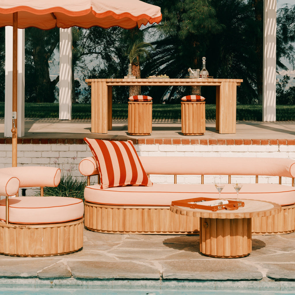 Outdoor patio setting with wooden furniture, striped cushions, and a large umbrella.