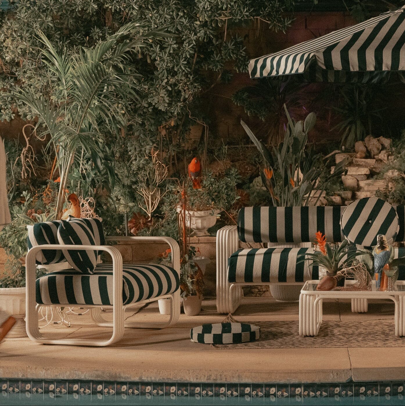 Product image of Outdoor patio set with striped furniture and umbrella near a pool