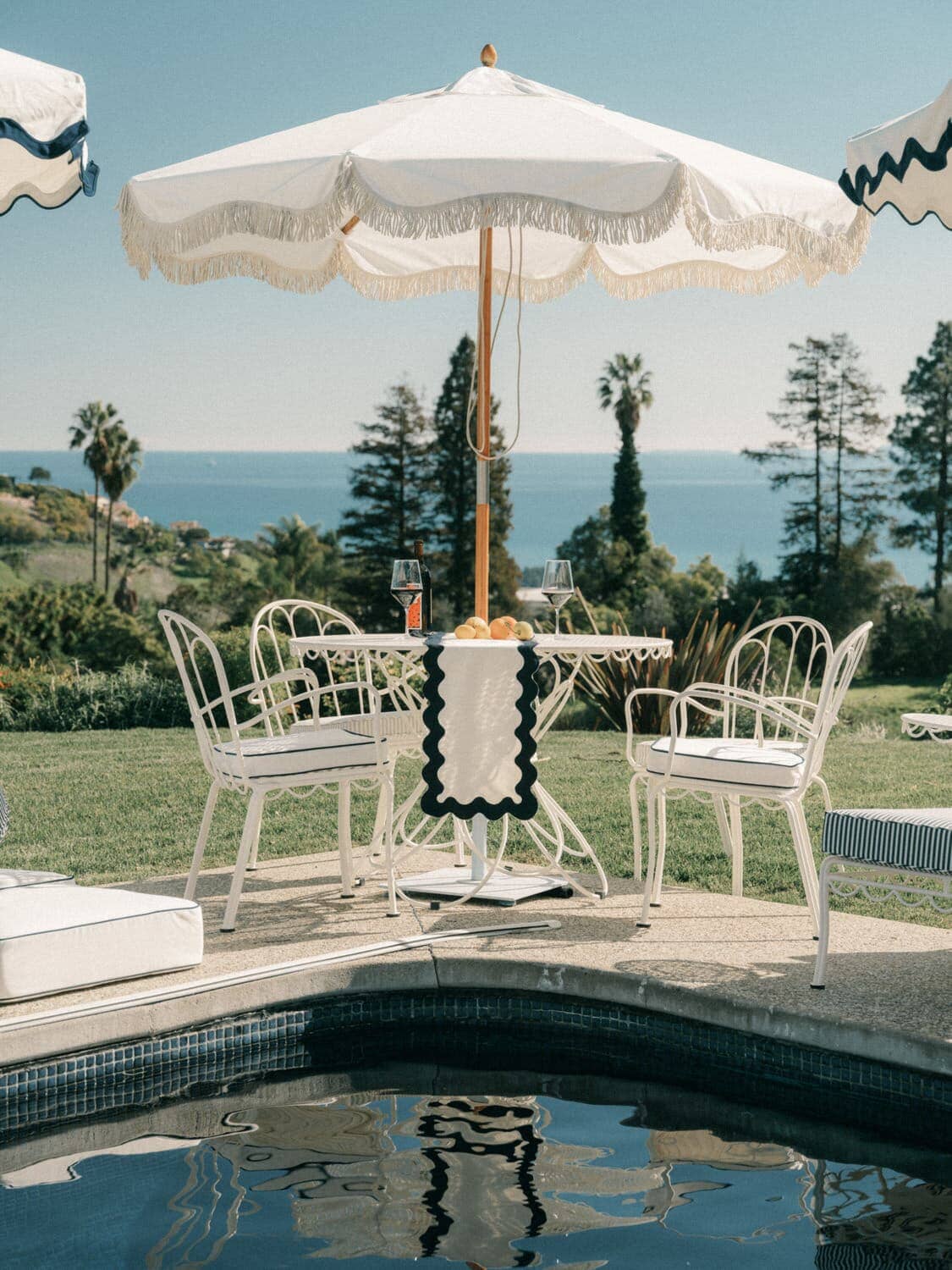 Outdoor dining table with chairs next to a pool