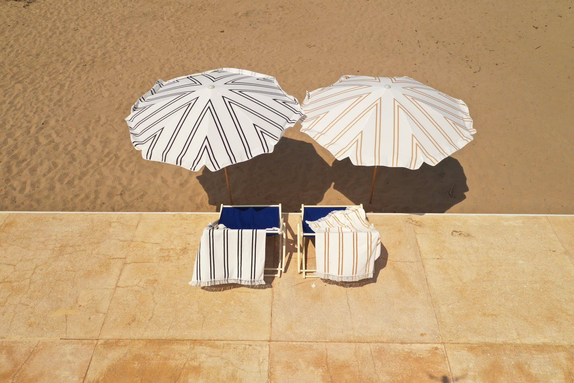 black two stripe & sand two stripe amalfi umbrella and tommy chair on the beach