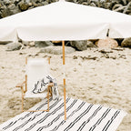 white amalfi umbrella at the beach with chair and blanket