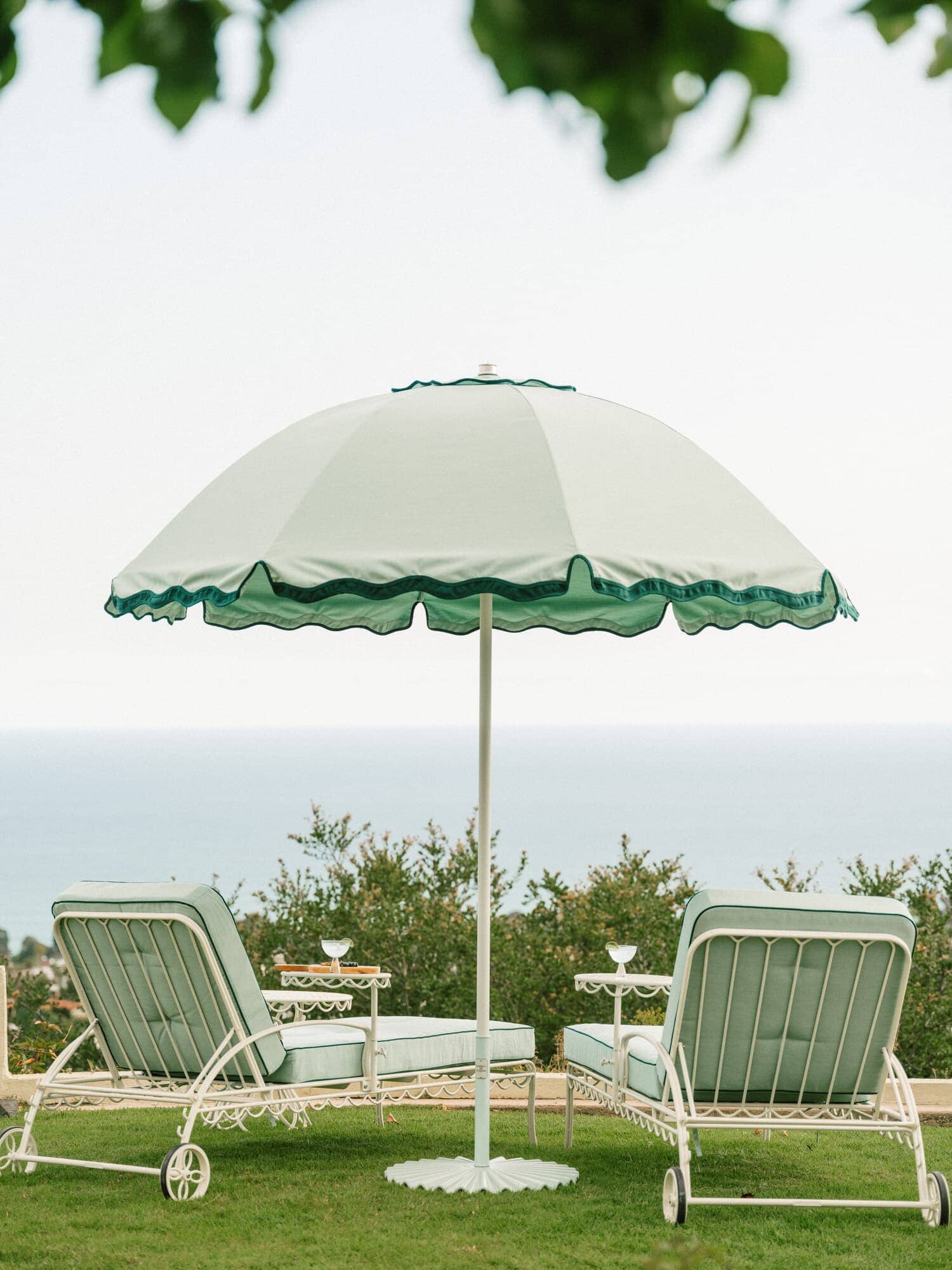 green patio umbrella and two sun loungers on a lawn