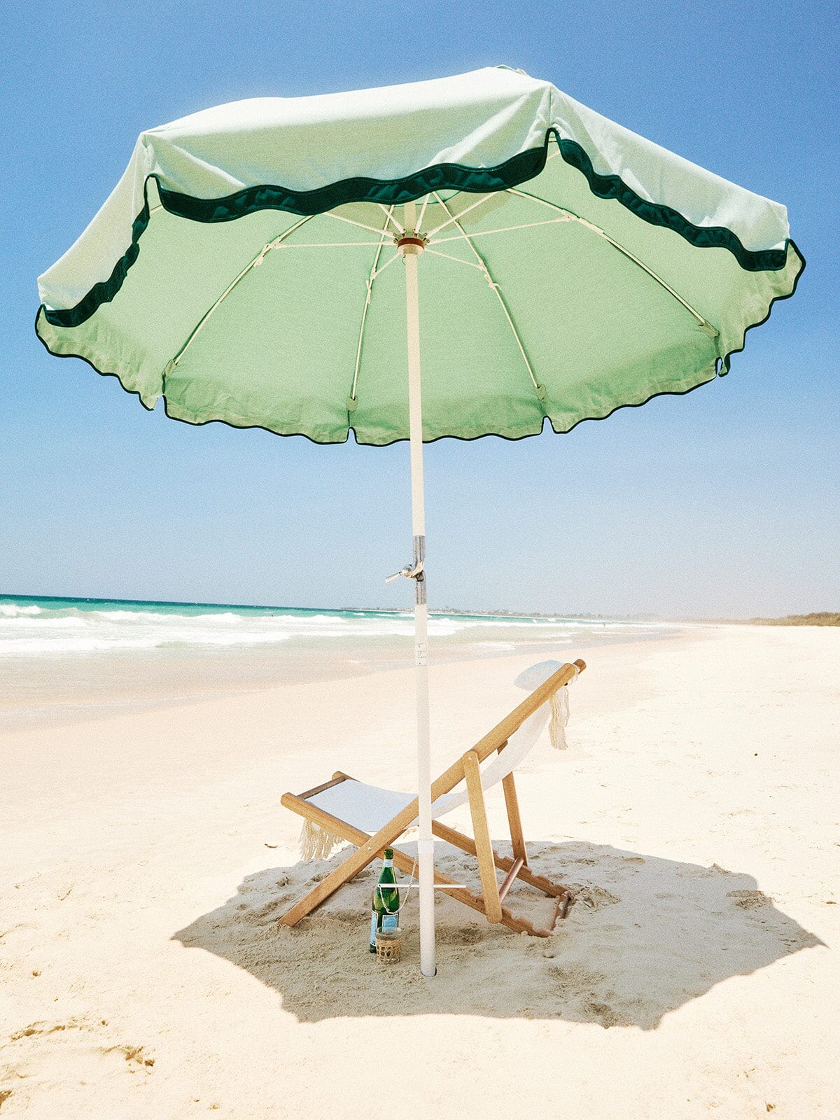 rivie green beach club umbrella and white chair on the beach