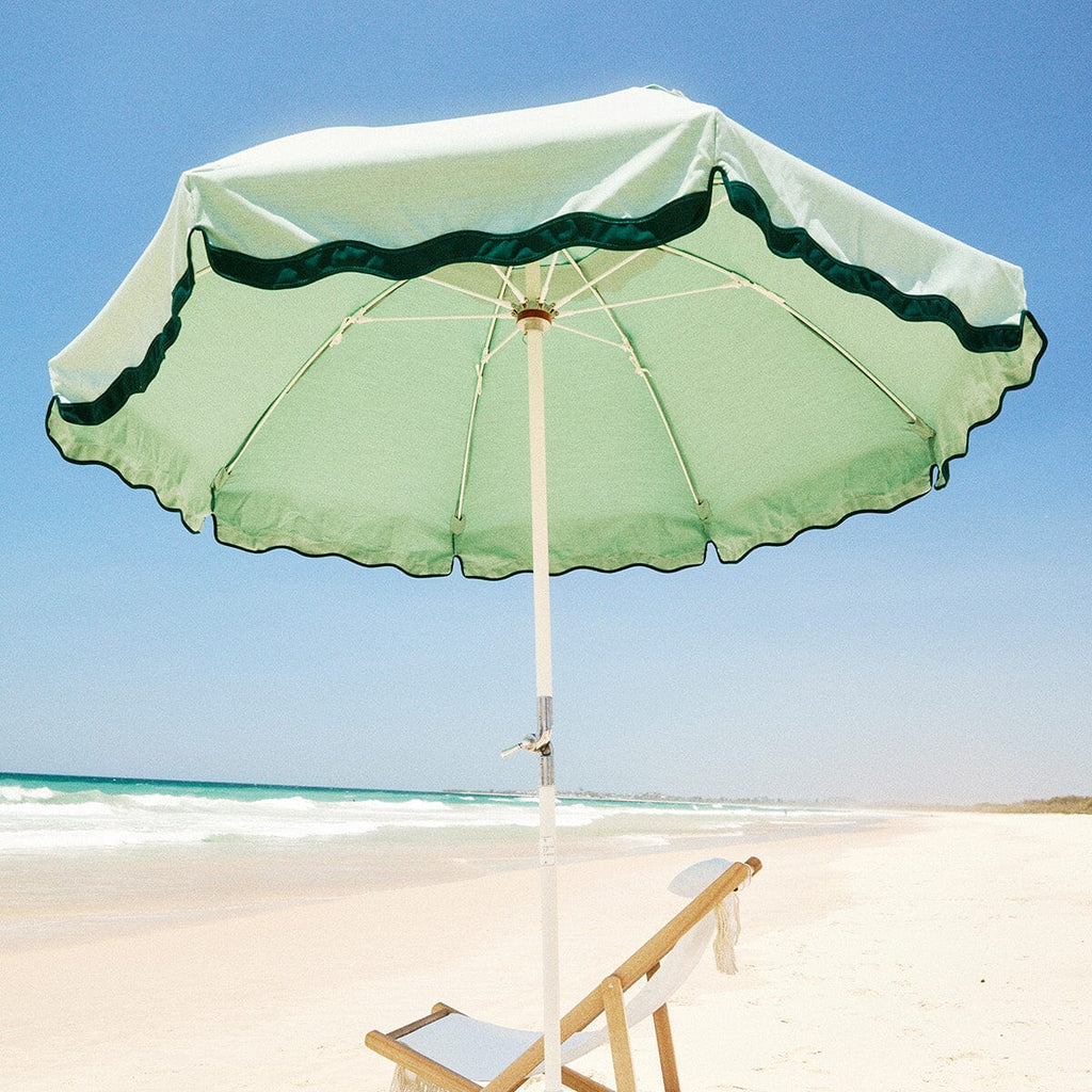 rivie green beach club umbrella and white chair on the beach