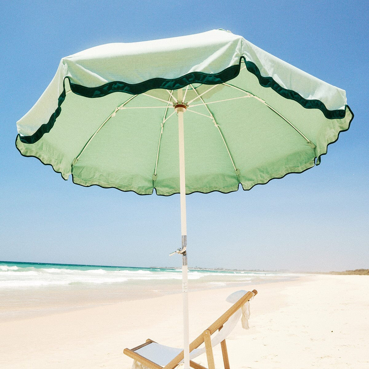 rivie green beach club umbrella and white chair on the beach