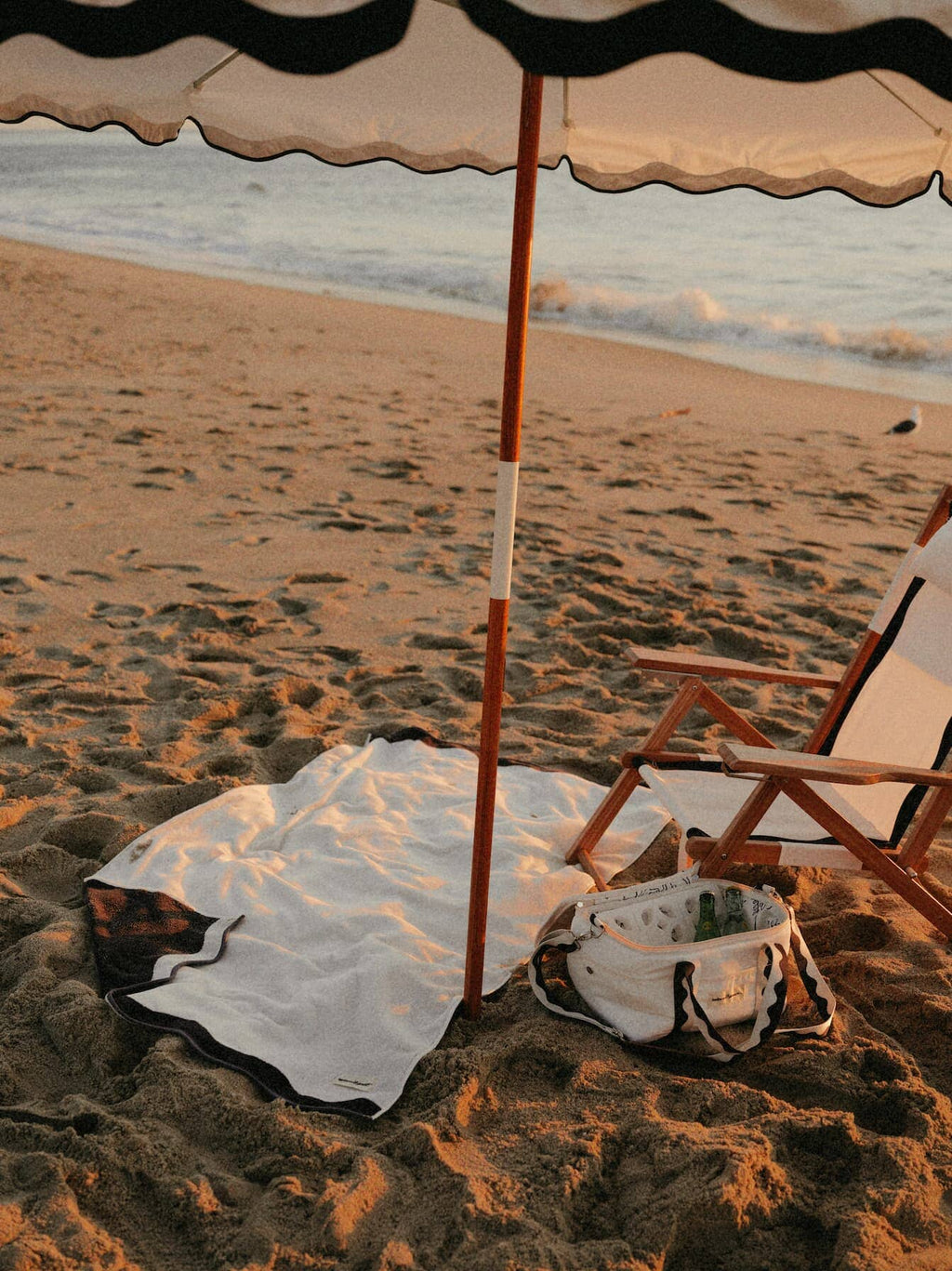 White riviera beach set up with umbrella, chair, towel and cooler