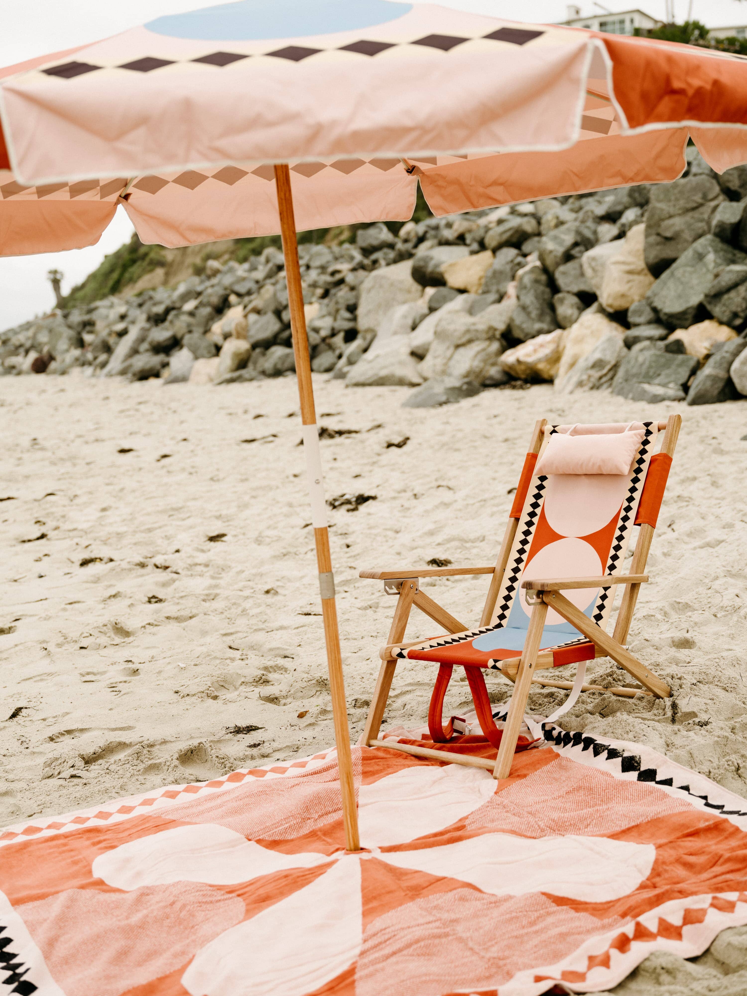 Beach set up with diamond pink umbrella, chair and blanket