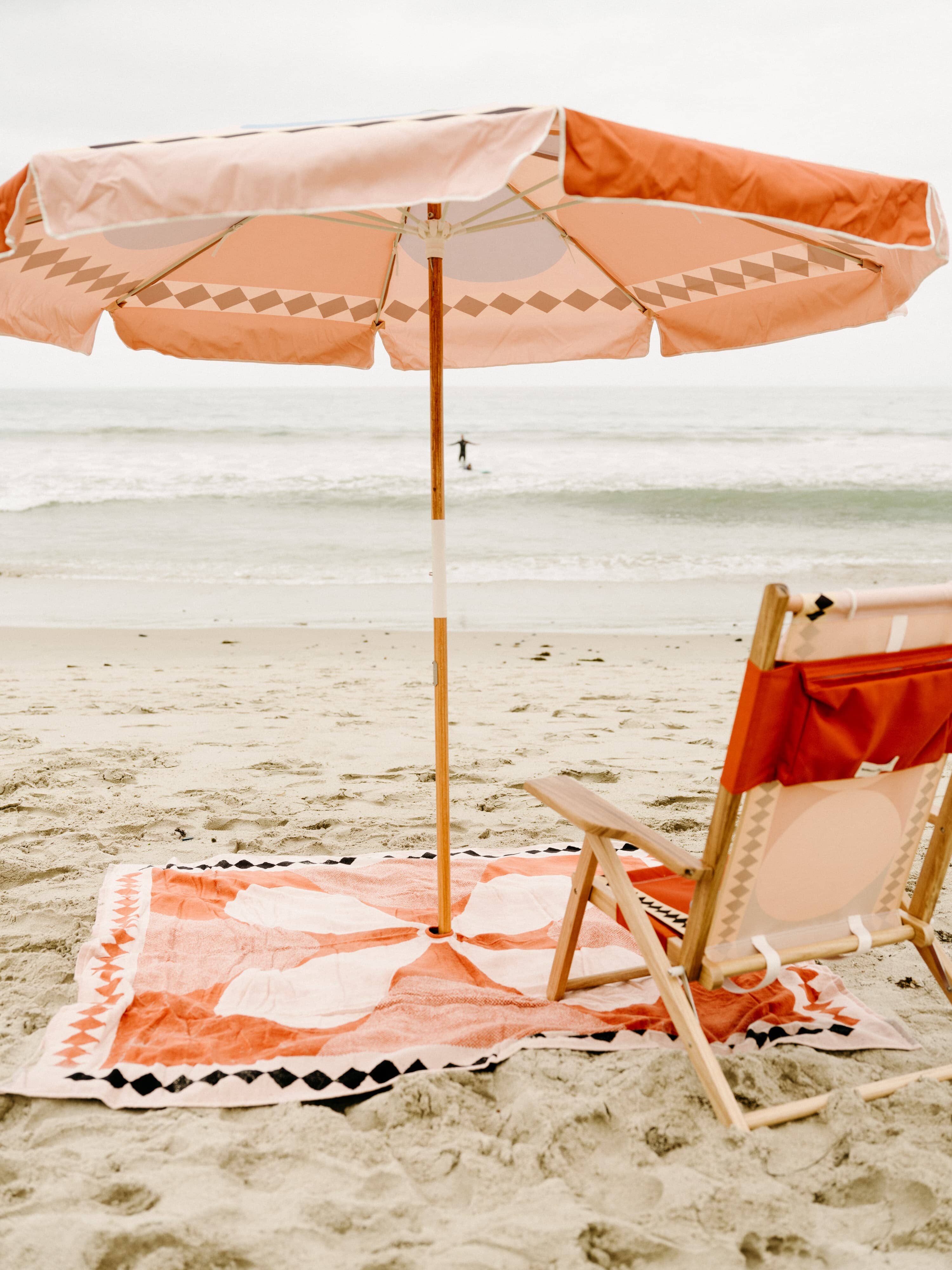 Beach set up with diamond pink umbrella, chair and blanket