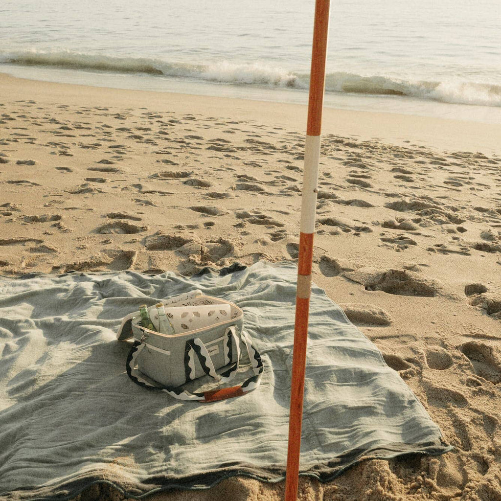 green riviera blanket on the beach with umbrella and cooler