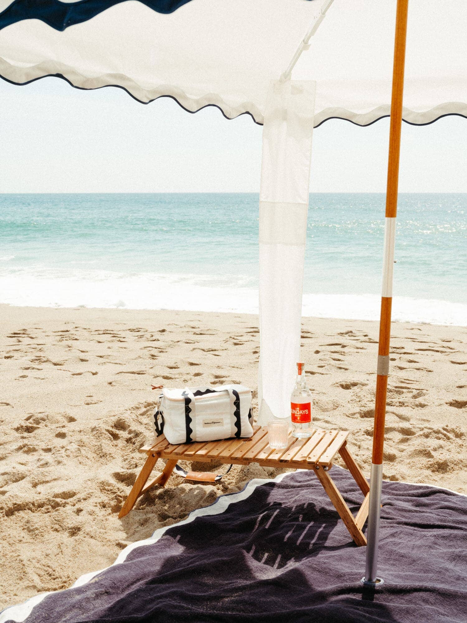riviera white blanket, cabana, cooler and table on the beach