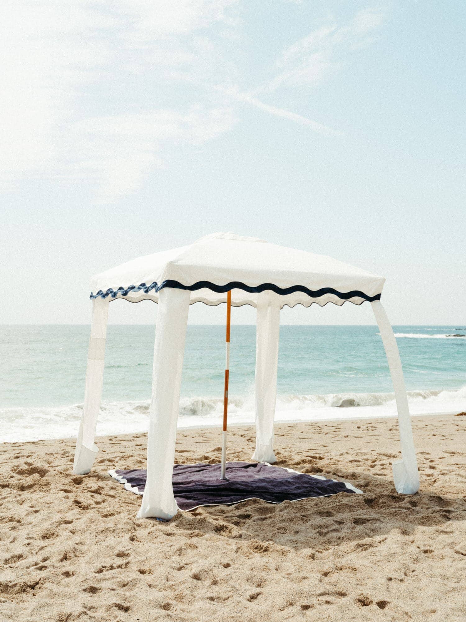 riviera white blanket, cabana, cooler and table on the beach