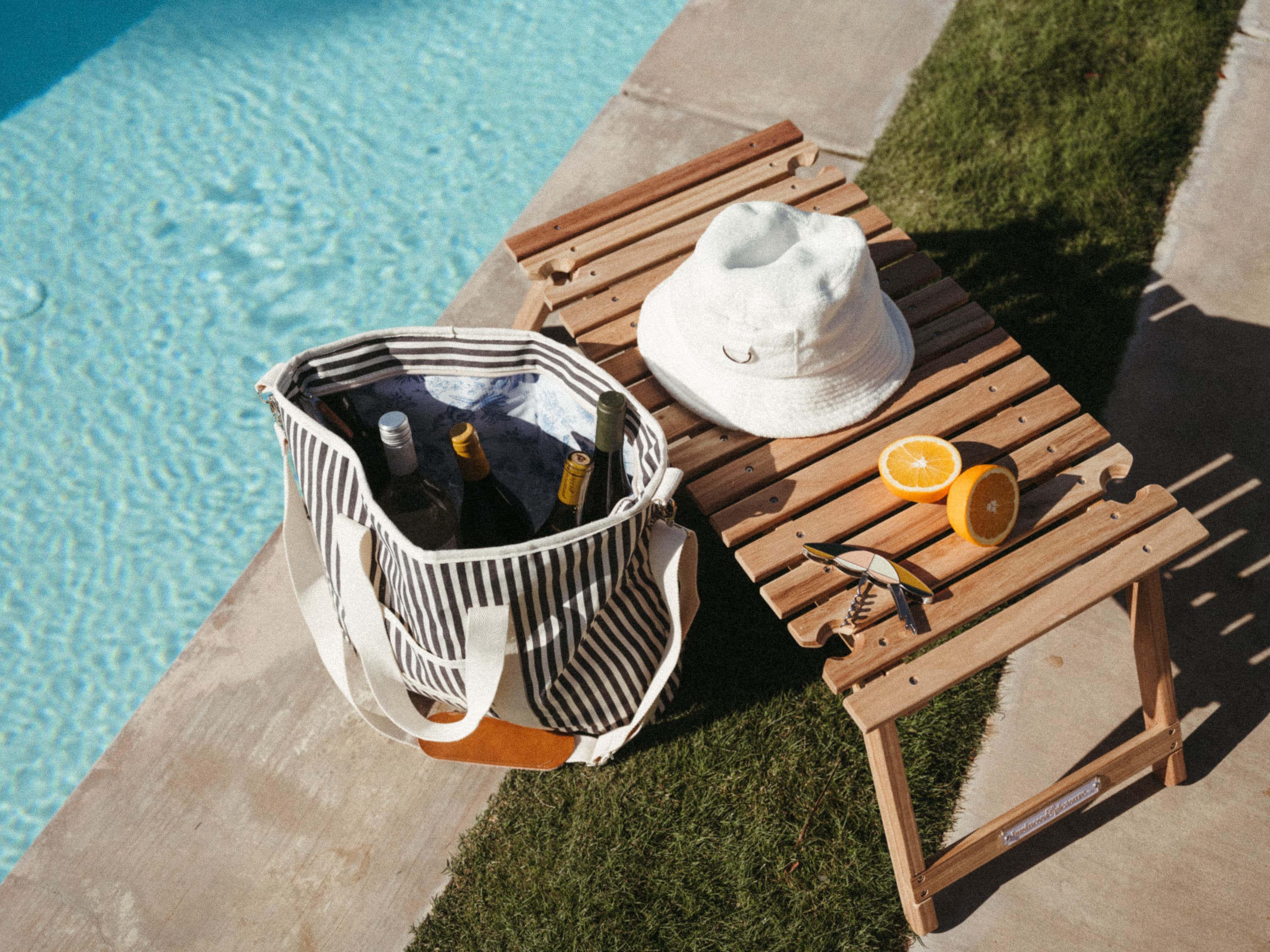 cooler tote bag and folding table next to a pool